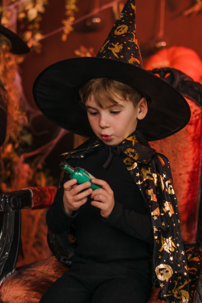 万圣节装饰中戴着黑色魔术师服装和帽子的可爱小男孩，万圣节概念图片下载