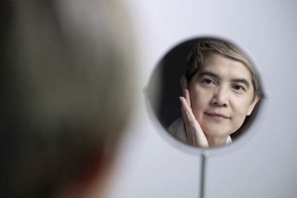 微笑成熟的女人宠爱和应用皮肤护理。图片下载