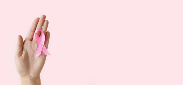乳腺癌宣传月。女人手握粉色缎带在粉色背景上。十月是乳腺癌的国际标志。医疗保健和医学概念。本空间图片下载