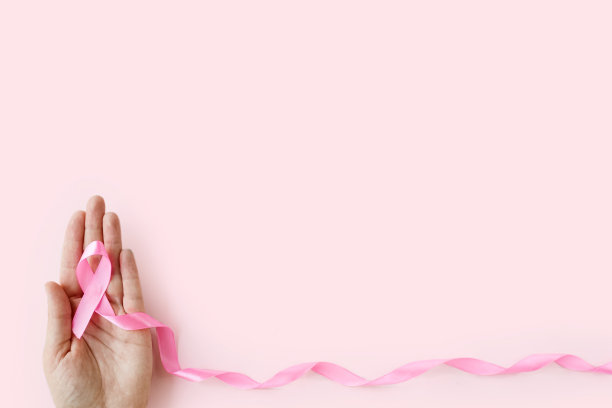 乳腺癌宣传月。女人手握粉色缎带在粉色背景上。十月是乳腺癌的国际标志。医疗保健和医学概念。本空间图片下载