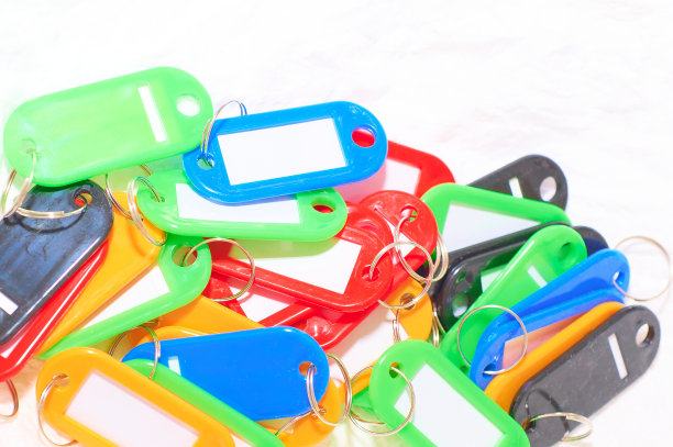 Keychain:不同颜色的塑料钥匙夹，白色背景，各种纸张，一个键盘，体现公司的组织和秩序概念。水平图片下载