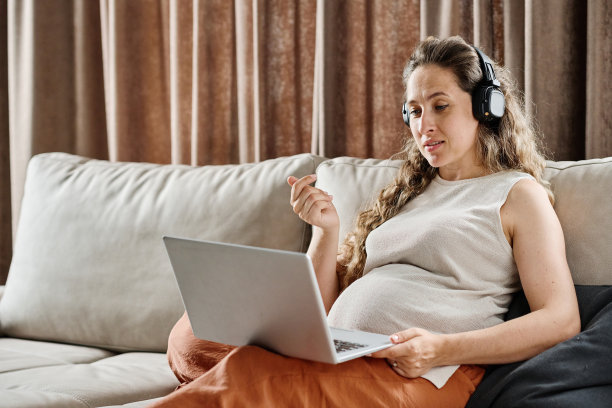 年轻自信的孕妇戴着耳机与人交流图片下载