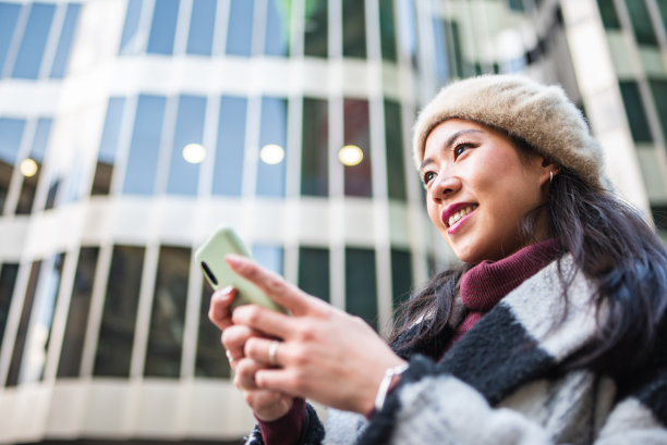 高兴的中国女子在城市用智能手机发短信图片下载