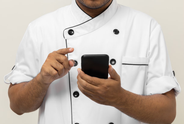 特写男手厨师拿着手机选择各种美味的菜式菜单好口味的顾客点单。在线智能手机外卖买菜多种多样。厨师与食谱在移动。图片下载