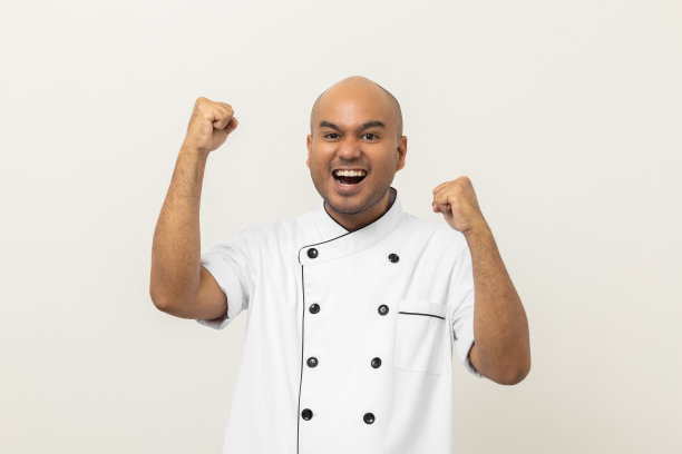 快乐微笑年轻英俊的亚洲人厨师在制服手臂伸展感觉成功的兴奋在孤立的背景。印度人的职业是厨房、餐厅和酒店的厨师或面包师。图片下载