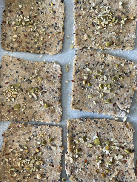 整幅图片，一排排新鲜出炉的自制脆饼干，上面放着切碎的坚果和种子，放在防油纸羊皮纸上，俯瞰全局图片下载