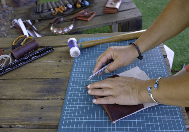 在她的小作坊里工作的工匠。用皮革制作钱包的工匠。图片下载