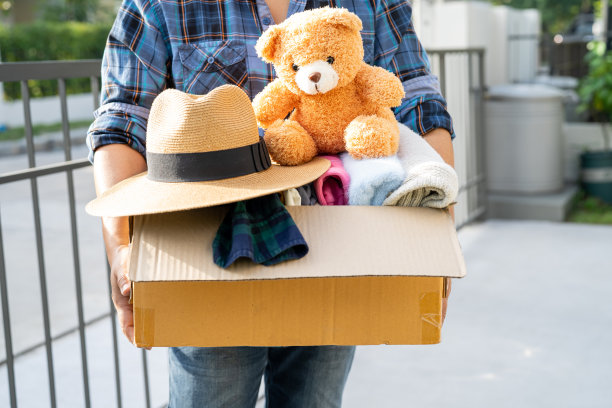 家里拿着衣物捐赠箱，里面有旧衣服和洋娃娃，支持帮助世界上的穷人。图片下载