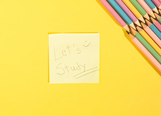 纸上信息标志特写。一个鼓励学习的帖子。黄色背景的彩色木制铅笔。带有拷贝空间的俯视图。回到学校概念。图片下载