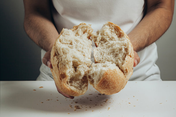 男人们用手掰开用酸面包做成的圆形小麦面包，露出里面的质地图片下载