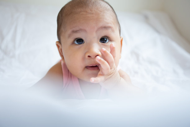 亚洲可爱宝宝在白色阳光充足的卧室。新生儿躺在床上放松图片下载