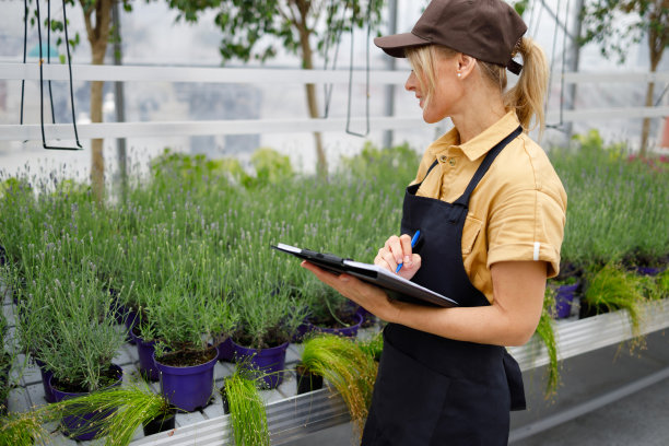 拿着写字板检查温室里鲜花质量的女人图片下载
