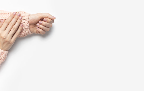 时髦漂亮温柔的美甲。年轻女子的手在粉红色针织毛衣上的白色背景俯视图平lay。天然指甲油，自我护理美容时尚。美甲美容院图片下载