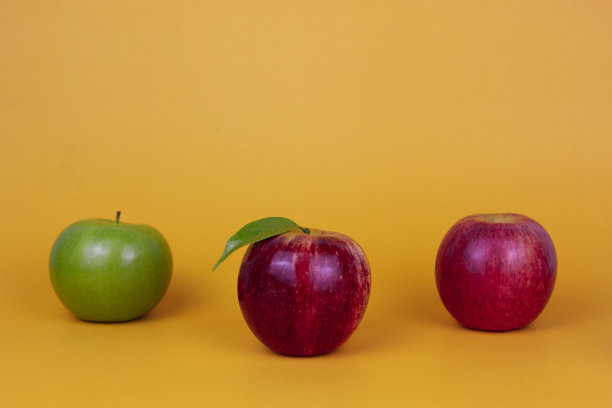 三个不同的苹果，绿色和红色的果实分离在黄色的背景。健康水果理念广告，绿色食品健康图片下载
