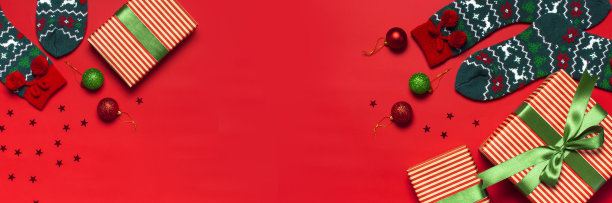 羊毛袜子与圣诞新年装饰，礼品盒，球，闪闪发光的五彩纸屑在红色背景俯视平lay。节日概念，呈现圣诞节。祝贺背景与空间的文本。图片下载
