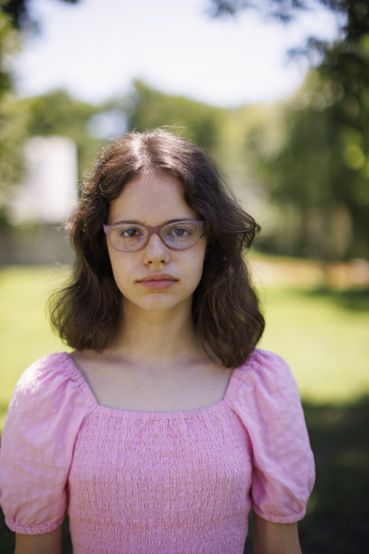 一个严肃的女孩与眼镜看相机的特写肖像图片下载