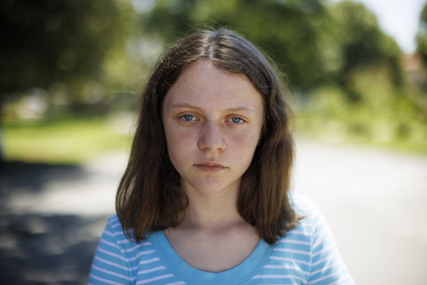 一个蓝色眼睛和雀斑的女孩的特写肖像认真地看着相机图片下载