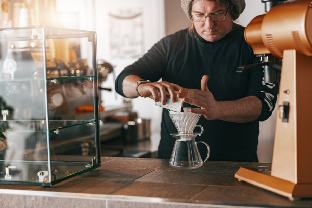 男咖啡师站在咖啡店的柜台上制作滴滤咖啡图片下载