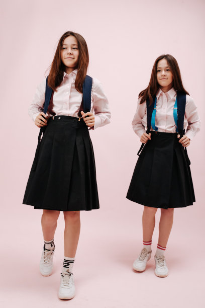一对双胞胎女学生拿着她们背包的背带。图片下载