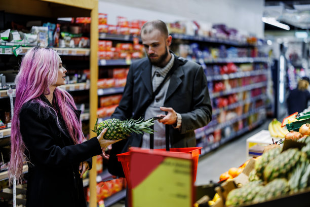 一对年轻夫妇在当地的市场商店买水果和蔬菜。图片下载