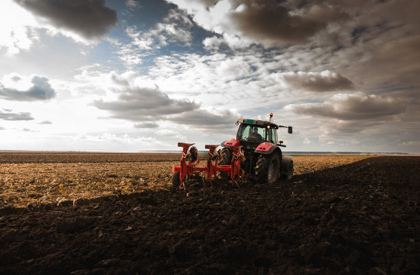 日落时拖拉机在田野上。图片下载