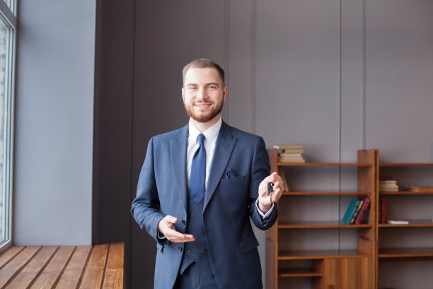 微笑着的年轻人拿出了房门钥匙。物业、所有权、新房和房地产概念。图片下载