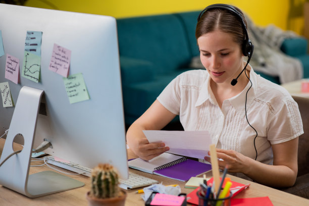 有魅力的女士呼叫中心代理在家里的电脑上工作，她准备了一些工作表与客户进行视频通话图片下载