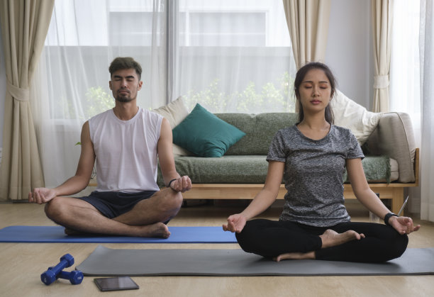 平静的夫妇冥想，坐在莲花姿势，在家里练习瑜伽。健康的生活方式，瑜伽，普拉提，运动理念。图片下载
