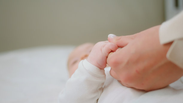 在镜头前，漂亮的宝宝和他的妈妈在一起，手牵着手，躺在床上，感觉很开心图片下载