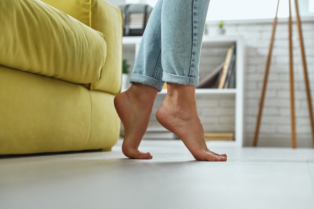 赤脚妇女站在家里温暖的木地板上的特写图片下载