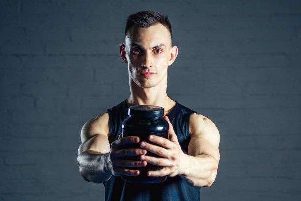 一个年轻人在健身房拿着一罐蛋白质图片下载