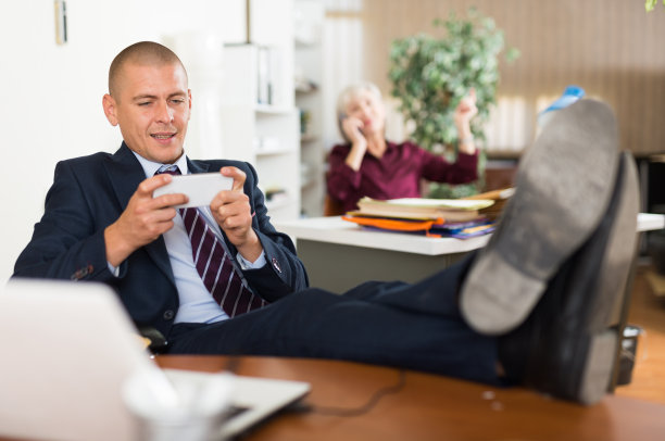 成年员工在办公室玩智能手机游戏图片下载
