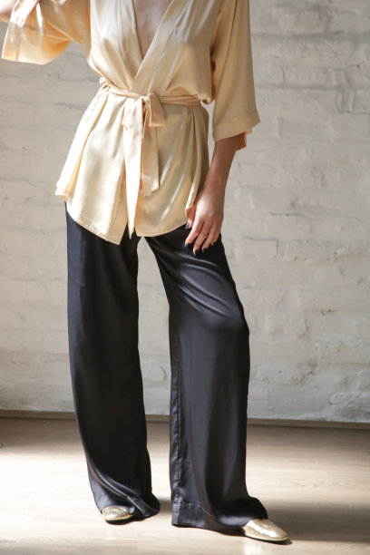 工作室系列形象的年轻女子米色丝绸长袍和黑色宽长裤图片下载