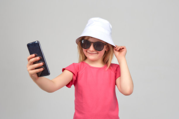 戴墨镜和白帽子的有趣女孩微笑着自拍图片下载