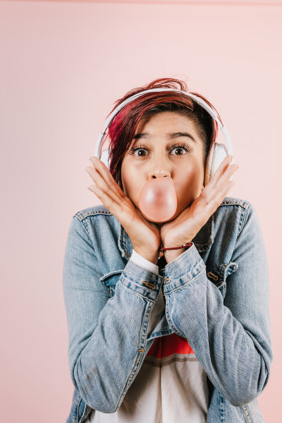 肖像拉美裔年轻女子与彩色头发嚼口香糖和耳机听音乐在墨西哥拉丁美洲图片下载
