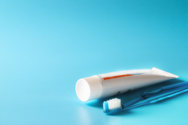 蓝色的牙刷和白色的牙膏，蓝色的背景，提供基本的牙齿护理理念图片下载