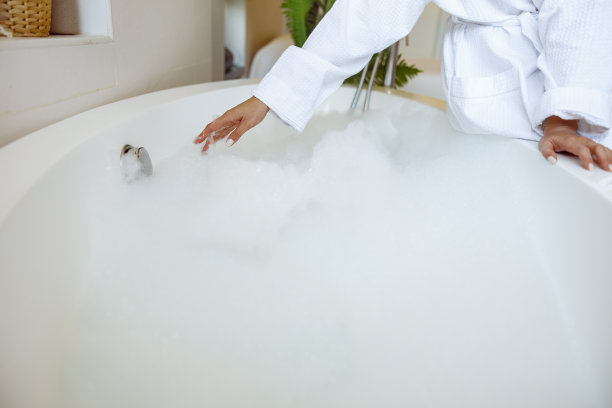 白种人女性准备热浴缸与泡沫和泡沫的特写。温泉在家里。图片下载