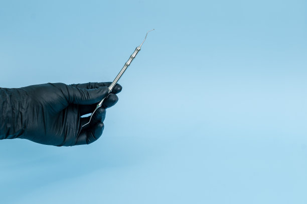 裁剪镜头的专业牙医在黑色医疗手套与牙科工具。牙科的概念。孤立在蓝色背景上图片下载