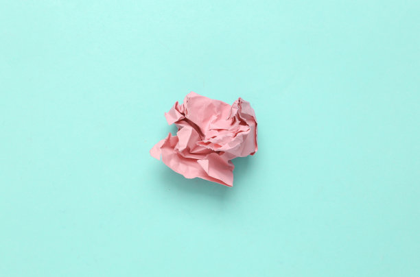 粉红色皱巴巴的一张纸在浅蓝色的背景。最小的静物图片下载