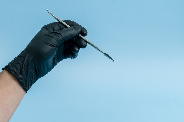 裁剪镜头的专业牙医在黑色医疗手套与牙科工具。牙科的概念。孤立在蓝色背景上图片下载