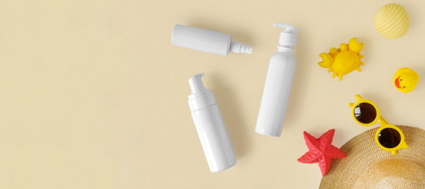 中性背景上的防晒乳管。米色桌子上放着塑料瓶防晒用品和儿童太阳镜和沙盒玩具。儿童护肤理念。对儿童防晒霜。婴儿化妆品。图片下载