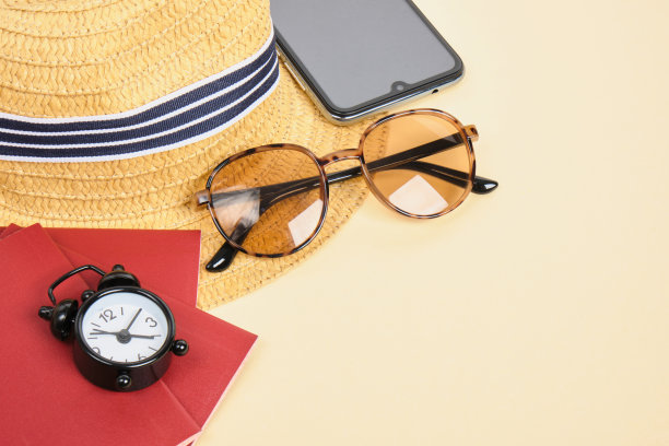 米色背景的草帽、太阳镜、闹钟和护照，旅行和海滩度假概念图片下载