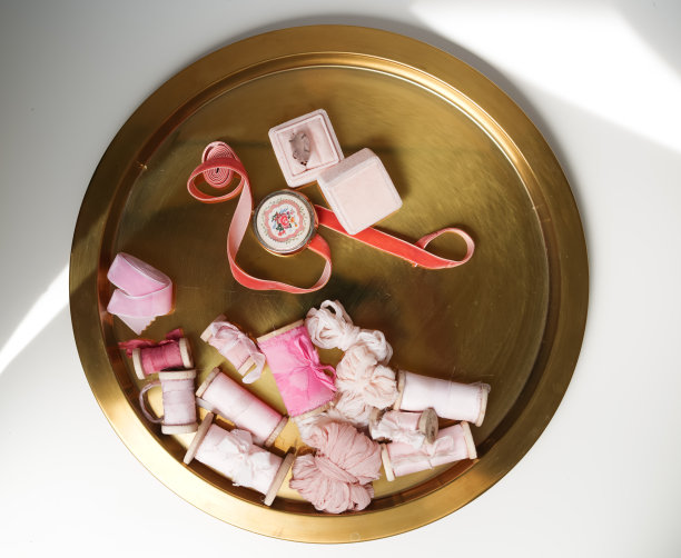 时尚婚礼的元素。日光下不同颜色的淡粉色丝带放在白色背景的金色底座上图片下载