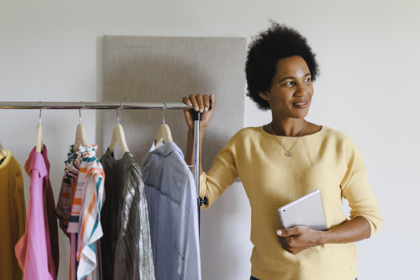 非洲女商人一边用电子平板电脑，一边把衣服装在纸箱里图片下载
