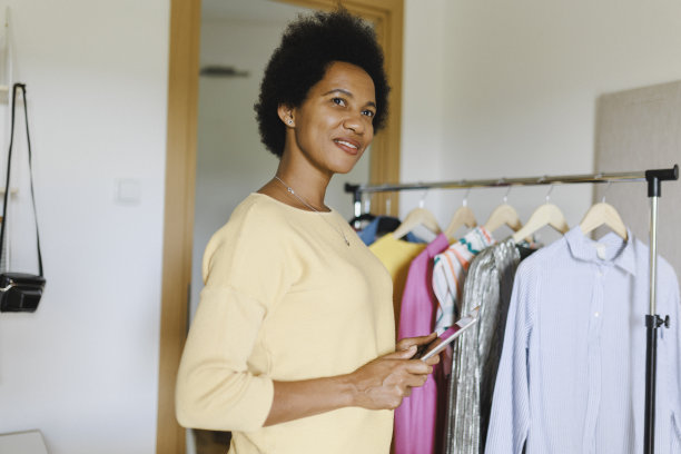 非洲女商人一边用电子平板电脑，一边把衣服装在纸箱里图片下载