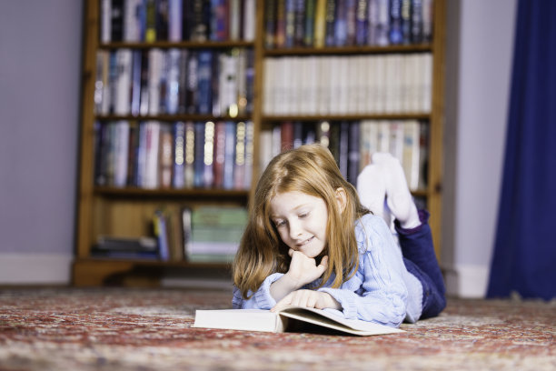 小女孩躺在地毯上看书图片下载
