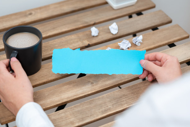 女商人拿着咖啡杯，用纸包着重要的信息放在桌上。女人在皱巴巴的备忘录上标注重要信息。图片下载