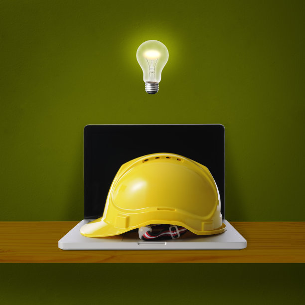 灯泡在半空中发光的笔记本电脑与黄色的安全帽图片下载