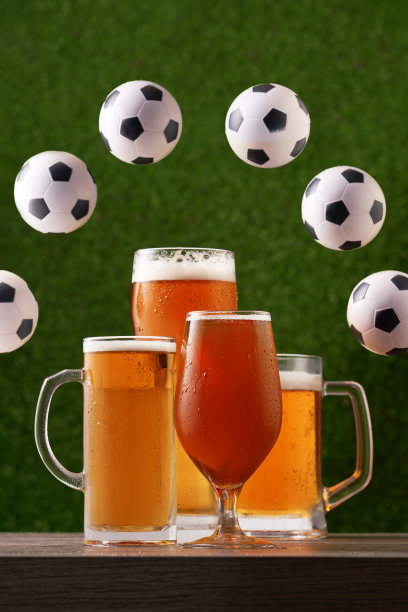 四杯啤酒与圆形框架从足球在绿色的草地背景。图片下载