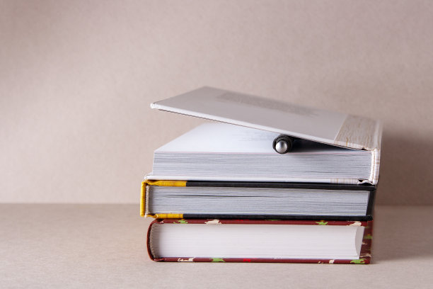 米色背景上的一叠课本和一支圆珠笔图片下载